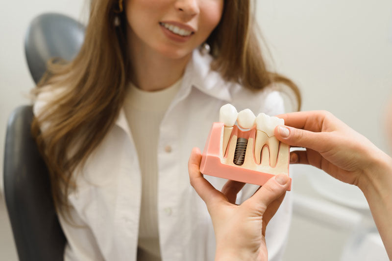 Dental Patient Getting Shown A Dental Implant Model During Her Consultation in New London, CT
